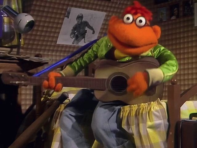 GIF of Scooter sitting on his bed playing the guitar