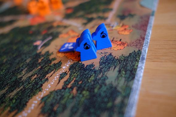 Three blue pointy wooden bird figurines on a tabletop game board.
