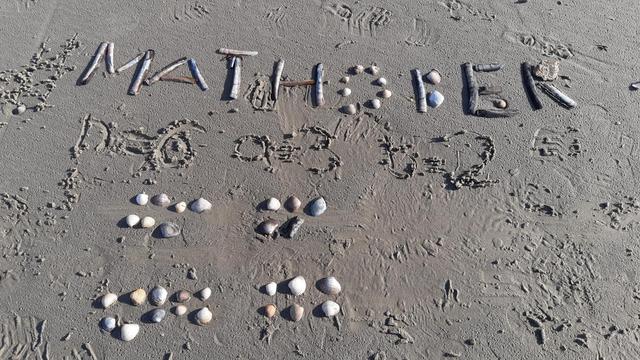 Seashells on the beach forming the word 'mathober' or arranged in 2 x 2 groups (7, 5 and 10, 6) shells.