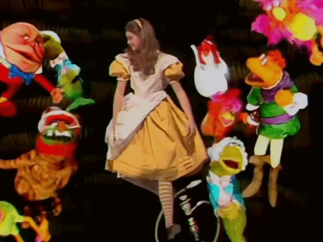 GIF of Brook Shields as Alice in Wonderland falling down the rabbit hole surrounded bu floating Muppets dressed as various Wonderland characters