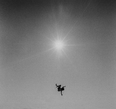 This photograph is titled "Icarus" and was taken in 1970 by the American photographer Adger Cowans.

The black-and-white image shows a small human figure, silhouetted against a bright, radiant sun in the sky, appearing to fall or float.

Adger Cowans (born in 1936) was an influential American photographer and a founding member of the art collective The Kamoinge Workshop. Among other roles, he worked as an assistant to the legendary photographer Gordon Parks at *LIFE* magazine.