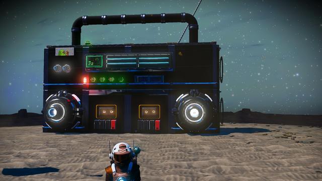 Someone used the no mans sky base building parts to build what looks like a giant dual cassette boombox.

It's largely black, with a handle along the top. there's a blue line midway along it that separates an upper portion with what looks like some tuning controls, along with a blob sticker on the upper left.

The lower half has two glowing machine things representing speakers and then two windowed objects with 2 glowing dots to be the tapes, and each one has 4 buttons underneath, the left 3 are black, and the rightmost one is red.

There's also the upper torso of  someone in a spacesuit space suit standing in front of it.