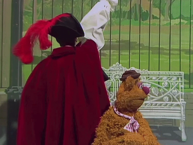 GIF of Glenda Jackson as a pirate captain ordering Fozzie's backdrop be raised up like a curtain revealing an elaborate pirate ship set full of Muppet pirates