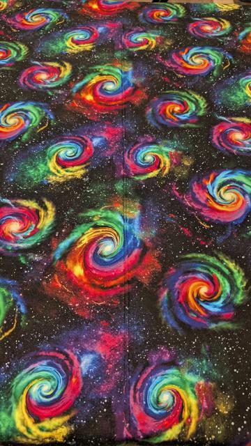Two pieces of fabric stitched together in the middle of the frame. The overall print is a bunch of vibrantly colored spiral galaxies and stars / gasses.