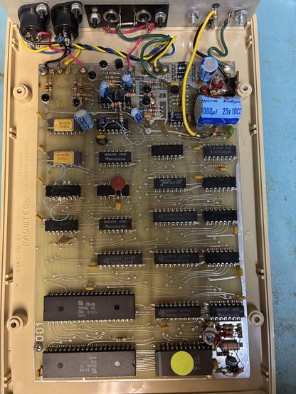A rather brownish-green PCB, with a lot of TTL DIP ICs, and two distinct 40 pin ICs near the front. 

One of those is the Z80 processor, and the other is an SIO. 

There’s also a pair of very nice gold and purple ceramic ADC ICs near the back, and a bunch of dead bugged components.
