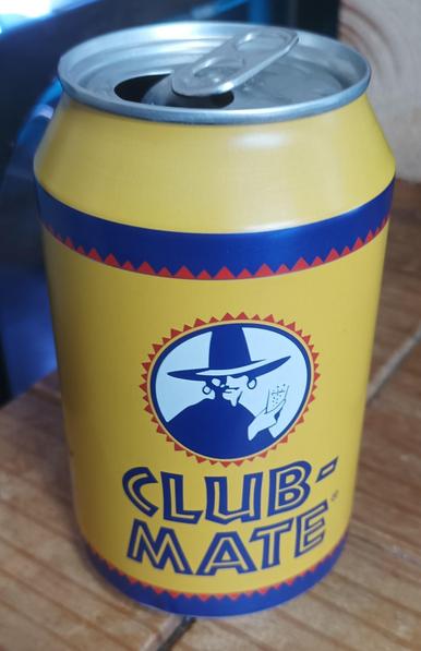 A yellow can with a large hatted person drinking a glass of fizzy liquid