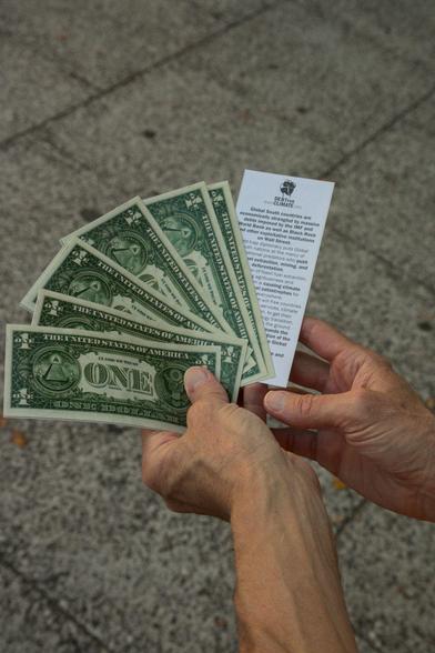 Dollar bills and a debt for climate leaflet of the same dimensios as the cash