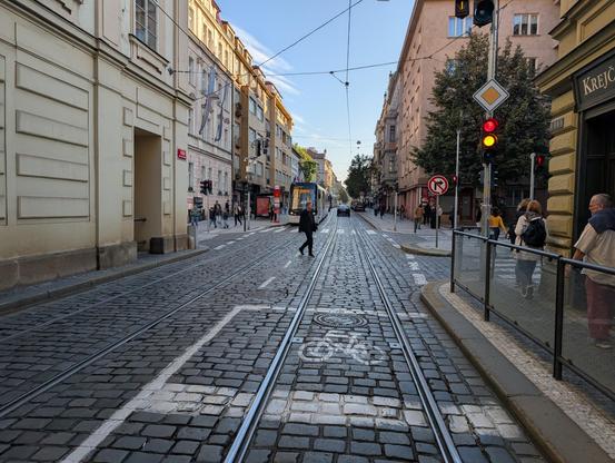 Cheap marking for a cycling area in front of a traffic light, on a paved street with tram tracks.
