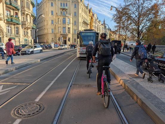 Cyclists waiting behind a tram, because the parallel lane is blocked by a car traffic jam.