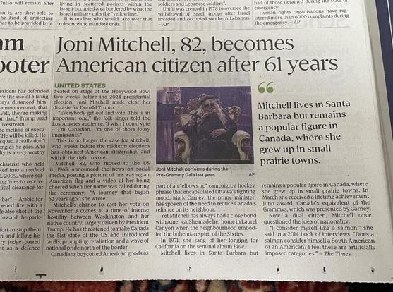 photo of a newspaper article, headline "Joni Mitchell, 82, becomes American citizen after 6l years" with a photo of the artist and a pullquote "Mitchell lives in Santa Barbara but remains a popular figure in Canada, where she grew up in small prairie towns."