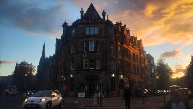 Four storey Victorian stone tenement corner building, with sunset skies above and behind it