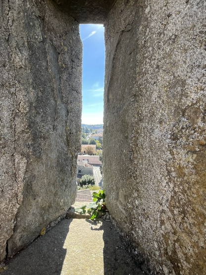 Kig ud på tage i Castellina in Chianti gennem et skydeskår. Himlen er blå, husene sandfarvede og stenen massiv
