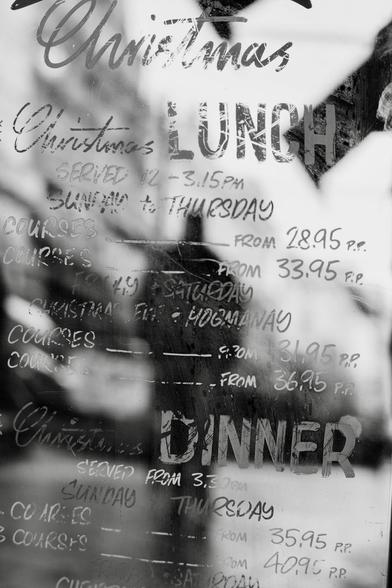 It is only October but restaurants are already advertising their Christmas menus and this one is doing so on a mirrored board in the street which is reflecting the outline of a man walking toward it.