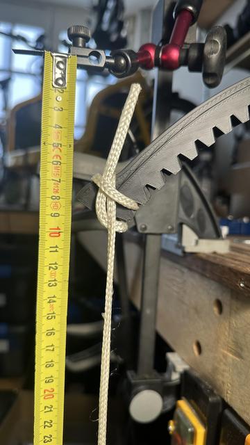 3d printed gear deflected by a 2kg weight tied to it. A tape measure is held by a magic arm to show 8cm of flex.