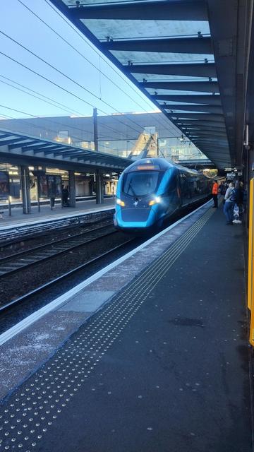 Sleek, modern, metallic blue train pulling up to the platform