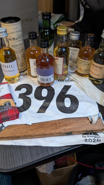 Photo of race number surrounded by 9 taster bottlea of whisky and a bit of a whisky cask and packet of shortbread