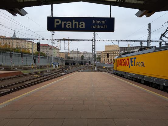 RegioJet Pool yellow locomotive from Alstom at the end of the platform under the sign "Praha hlavní nádraží".