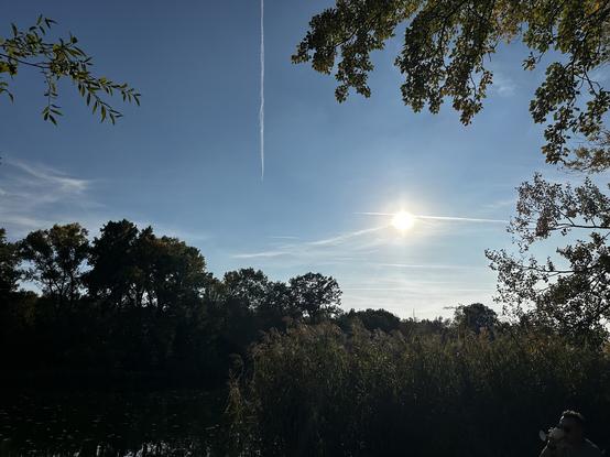 The sun bursts through and a plane trail slashes the sky in half