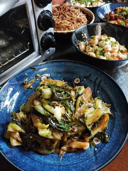Bok Choy with scallions in the foreground, Salt and pepper shrimp and Dan Dan noodles in the background to the left.