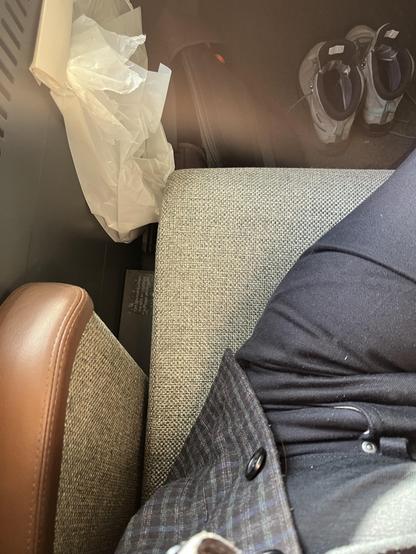 Kig ned på mit sæde. Jeg er i sorte jeans og mørk jakke, sædets stof er vævet af noget lysebrunmeleret garn (ligner uld, er nok poly-blanding fordi slid). Armlænet er chokoladebrune læder. På gulvet ser man mine vandrestøvler parkeret uden mine fødder i.