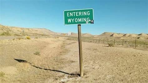 Remote path with a small and simple sign, on a post, that reads Entering Wyoming.