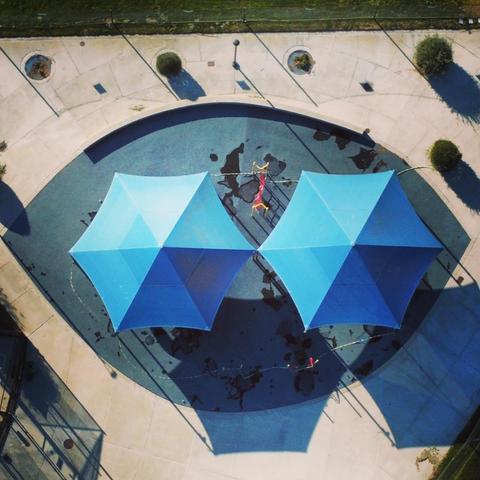 Artsy drone photo of two table umbrellas with some interesting ground features around them.