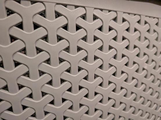 A closeup photo of a plastic laundry basket with a hexagonal weaving pattern on it.