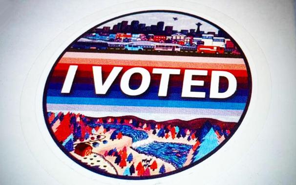 Circle sticker that says "I VOTED" across center with red, white and blue graphic on top of Seattle skyline and graphic on bottom of a King County forest, farms and river