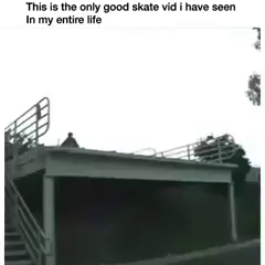 Grainy badly lit overcast... someone skateboards off of a about 1 story high concrete ledge over a large parking lot by a warehouse building.  Flailing arms, but lands it.  Video follows them for a moment as they skate off... then pans back to the ramp where a blue car drives off the edge and basically faceplants and smashes itself up.  Hood buckles.