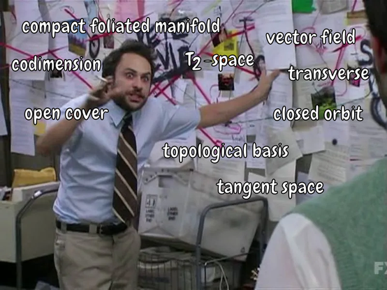 The meme image from "It's Always Sunny In Philadelphia" where Charlie Kelly presents his conspiracy theory in front of a wall with lots of papers and strings. Overlayed on the image are math terms like "compact foliated manifold", "tangent space" or "codimension".