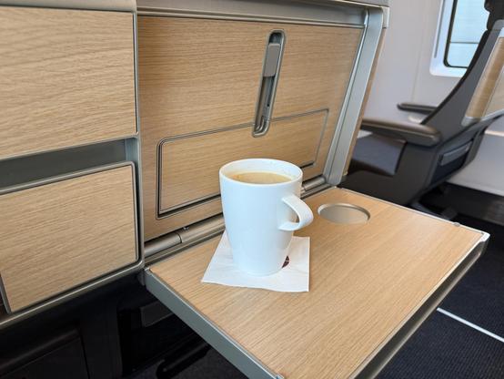 A mug of coffee on a railway trail table. It is about 12 cm tall.