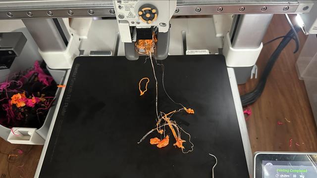 3d printer with extruder completely jammed with filament and blobs of it on the print bed.  the screen in the bottom right corner says "Printing Completed"