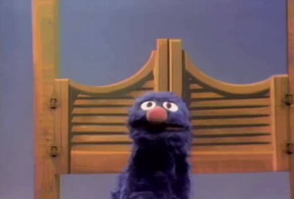 GIF of Sesame Street's Grover fainting though a swinging door