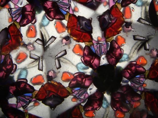 photo shot through the window of a sheryl koch kaleidoscope. the prisms make some obvious hexagonal reflections of purple, red, orange, and blue bits of fused art glass.