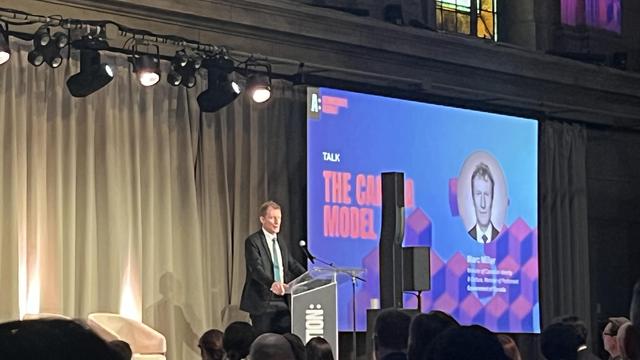 A speaker stands onstage in front of a slide that reads “the Canadian Model” (of tech policy)