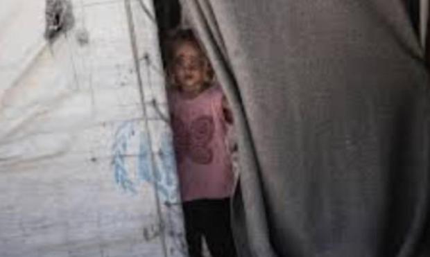 Une enfant à l’entrée d’une tente des Nations Unies.