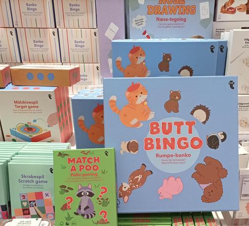Photo of a shop shelf with a box that says Butt Bingo, and another that says Match a Poo. Both have cute animals on them and are probably designed for kids.