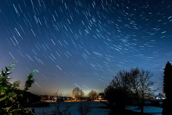 Timelapse image of stars swirling over a forest