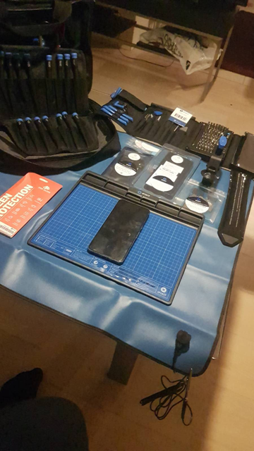 A Pixel 8 Pro laying on a iFixIt project mat. Above the project mat is a new battery and a new screen. There are also various tools spread around.