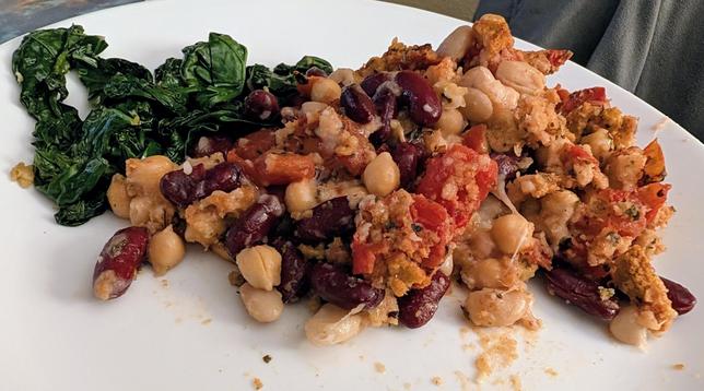 A plate with sautéed kale (not low effort) and a pile of casserole: beans of 3 types and diced tomatoes and stuffing bits, with cheese strung between it all