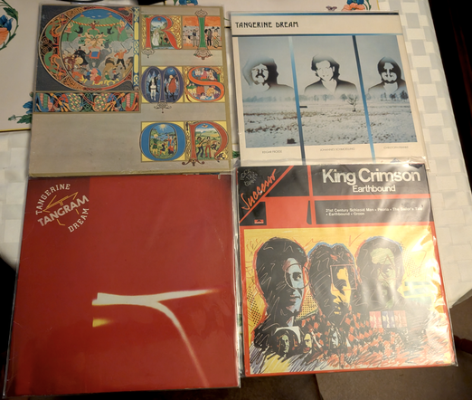 four vinyl records on a table: King Crimson - Lizard, King Crimson - Earthbound, Tangerine Dream - Poland, Tangerine Dream - Tangram