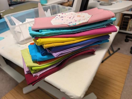 16 fabrics spanning the rainbow, in pastels and brights. An octagon of white fabric with swallows and stars in blue, purple, orange, and red sits on top.