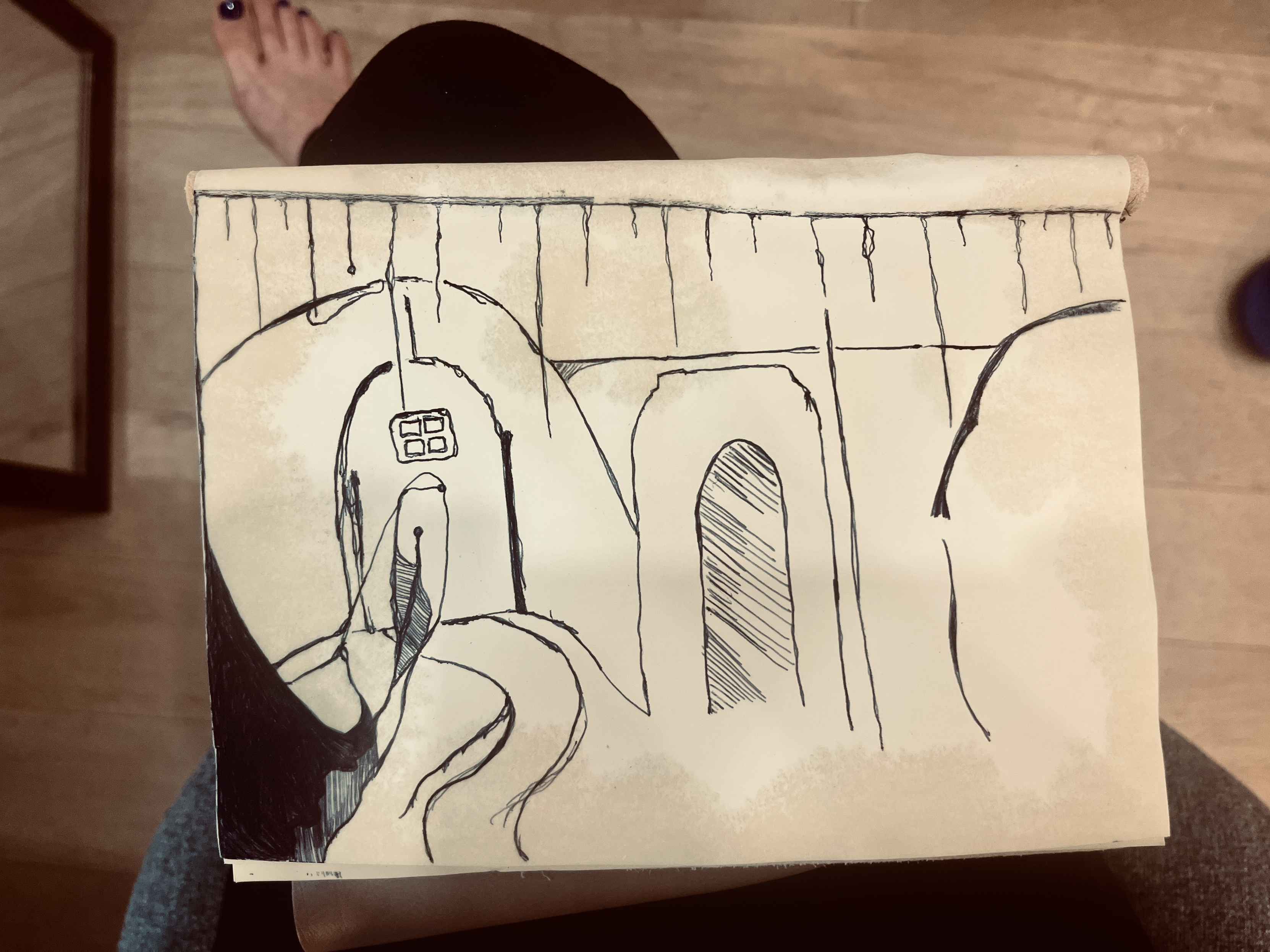 my dream journal opened to the back page, on my lap. the back page has a largely abstract drawing that shows doorways and paths leading up to them, with lines extending down vertically from the top. it's in black ink and it's very sketchy. in the background you can see i'm wearing black pants, and my floor is hardwood.